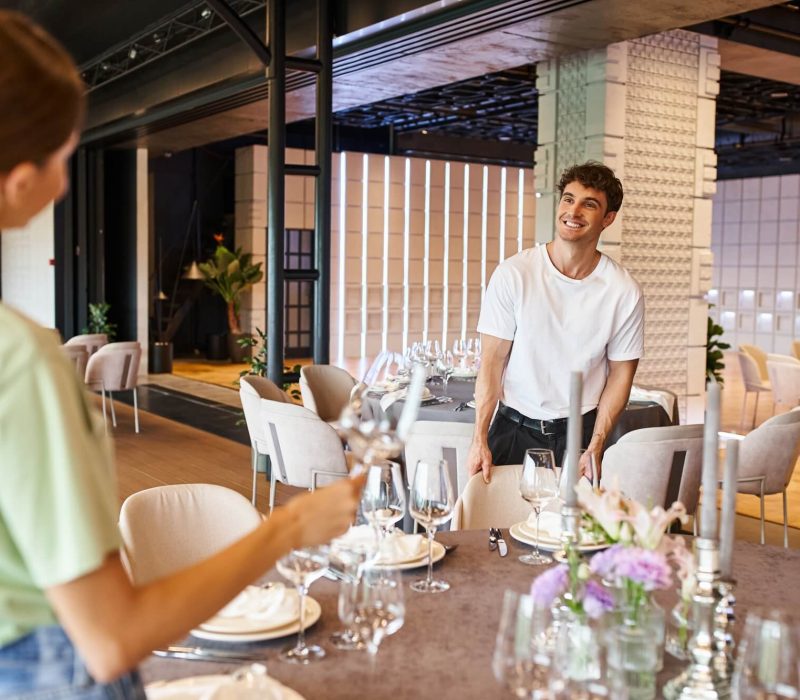 smiling-man-near-festive-tables-looking-at-woman-on-blurred-foreground-banquet-organizers-at-work